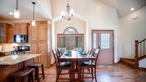 Una cocina amplia con armarios de madera, una isla grande y un comedor con mesa y sillas de madera.