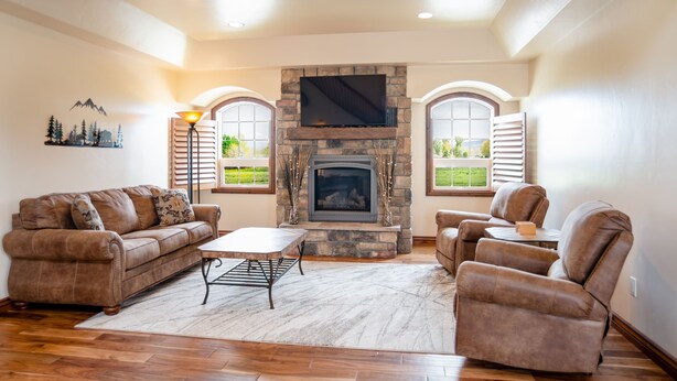 Una sala de estar con chimenea de piedra, un sofá, un sillón reclinable y una mesa de centro.