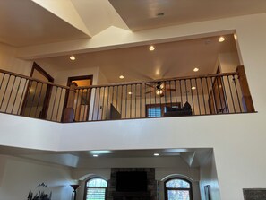 Un interior de varios niveles con escalera, chimenea y ventilador de techo.