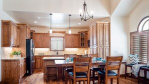 Una cocina amplia con armarios de madera, una isla central y un comedor con sillas.