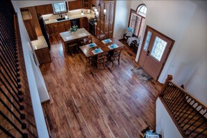A spacious kitchen with wooden cabinets, a dining table set for four, and a staircase leading to an upper level.