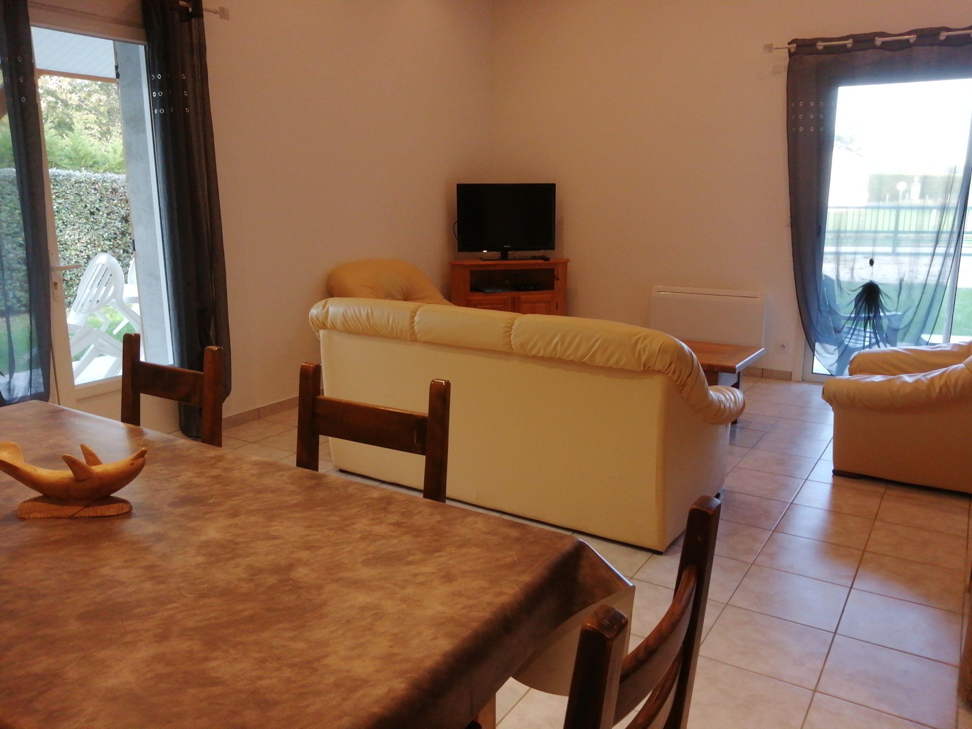Una sala de estar con un sofá, un mueble para televisión y una mesa de comedor.