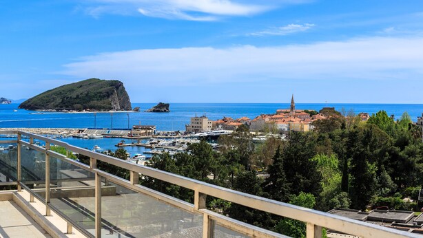 A coastal town with a marina, a prominent hill, and a church.