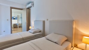 A hotel room with two single beds, a desk, and a chair.