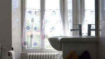 A bathroom with a window, a radiator, a sink, and a towel rack.