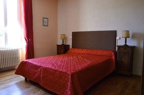 A room with a bed, two bedside tables with lamps, a radiator, and a window with curtains. - Le Vieux Noyer (Réaux sur Trèfle)