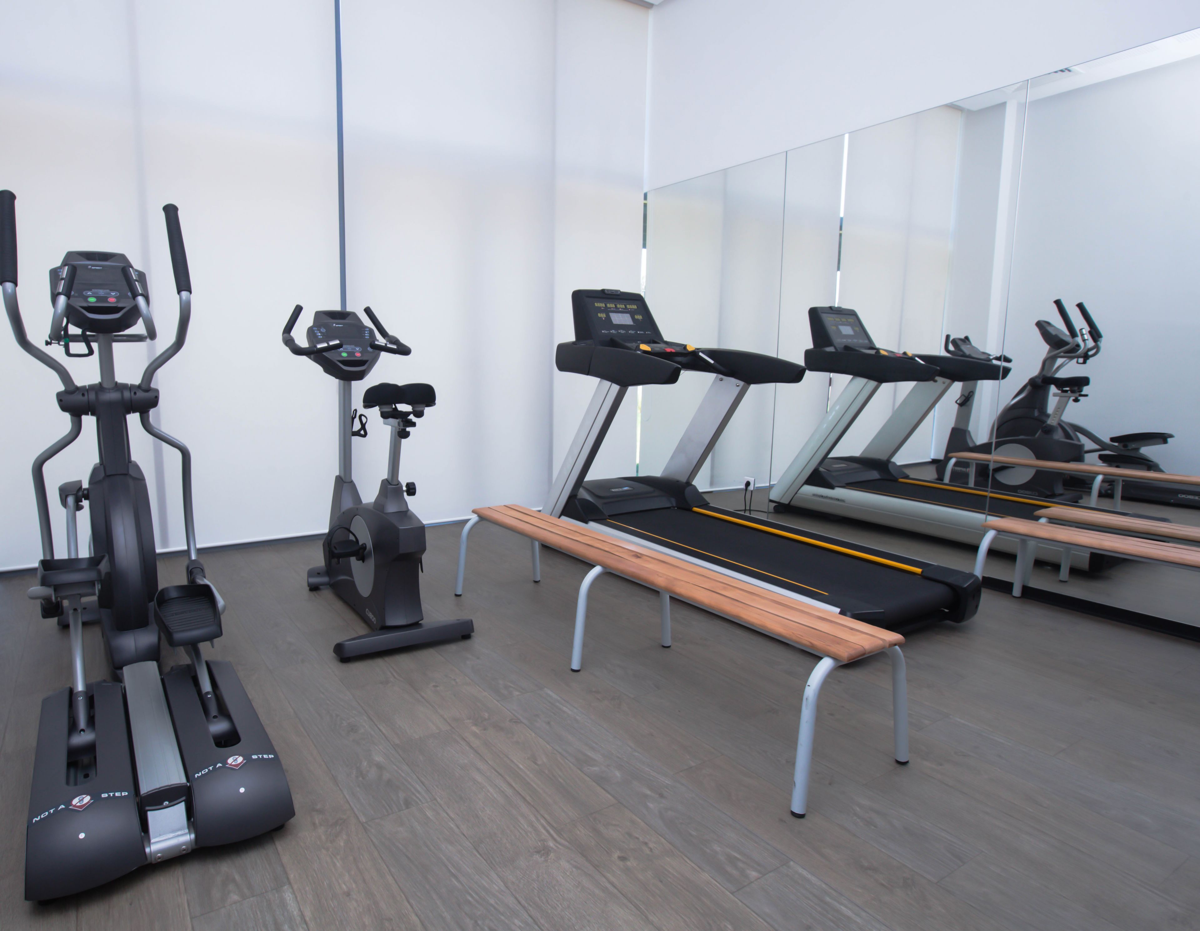 Une salle de sport équipée de divers appareils d’exercice, notamment des tapis de course et des vélos d’appartement.