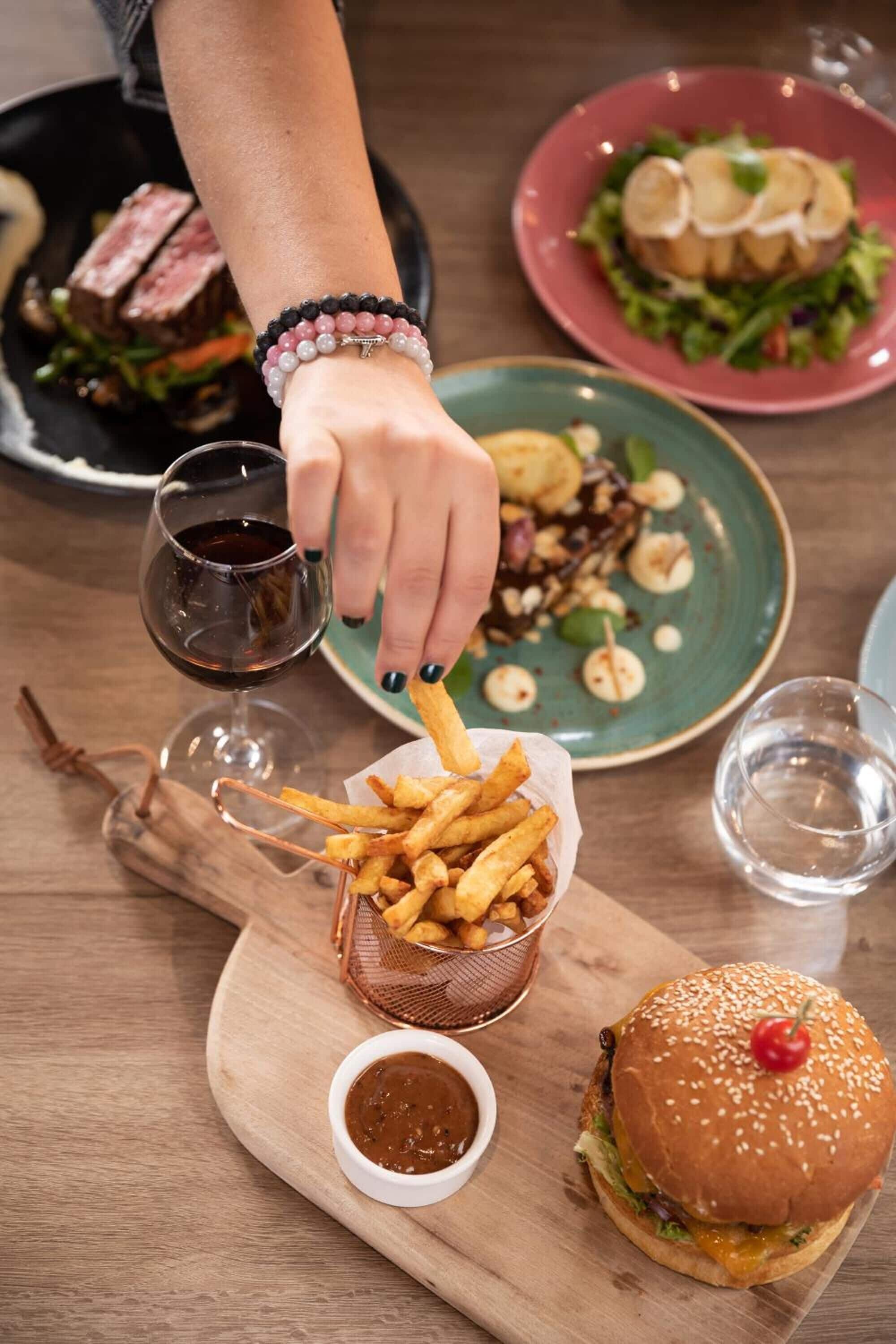 Una mesa de comedor con una hamburguesa, papas fritas y una ensalada.
