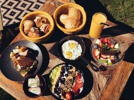 Ein Esstisch mit Croissants, Brot, Eiern, Obst, Joghurt und Milch.