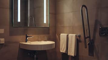 Un baño moderno con lavamanos, espejo, toallero y retrete.