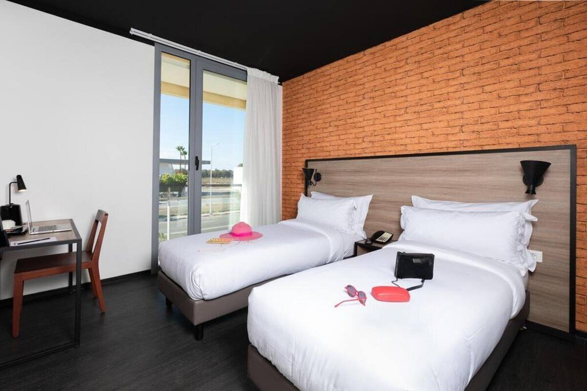 Une chambre d’hôtel avec deux lits, un bureau et un ordinateur portable.