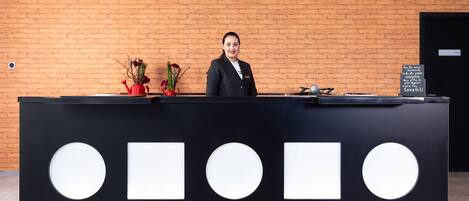A reception desk with a black and white design, a potted plant, and a sign with text.