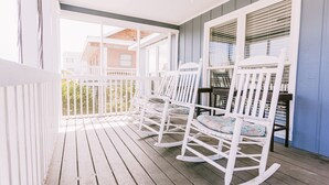 A porch with white rocking chairs and a wooden floor. - 3 bedroom-2 bathroom Beach house in the heart of Garden City/Murrells Inlet (Murrells Inlet)