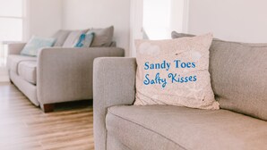 A living room with two grey sofas, one with a pillow that reads "Sandy Toes Salty Kisses". - 3 bedroom-2 bathroom Beach house in the heart of Garden City/Murrells Inlet (Murrells Inlet)