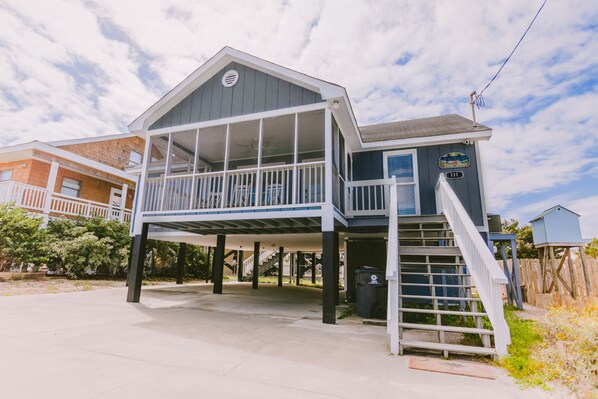 A two-story house with a balcony, a covered porch, and a staircase leading to an upper level. - 3 bedroom-2 bathroom Beach house in the heart of Garden City/Murrells Inlet (Murrells Inlet)