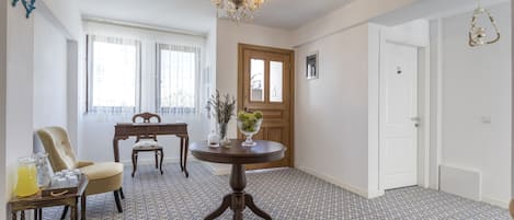 Een kamer met een patroon vloer, een kroonluchter, een eettafel met stoelen en een deur.