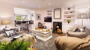 A modern living room with a fireplace, seating area, and a dining space.