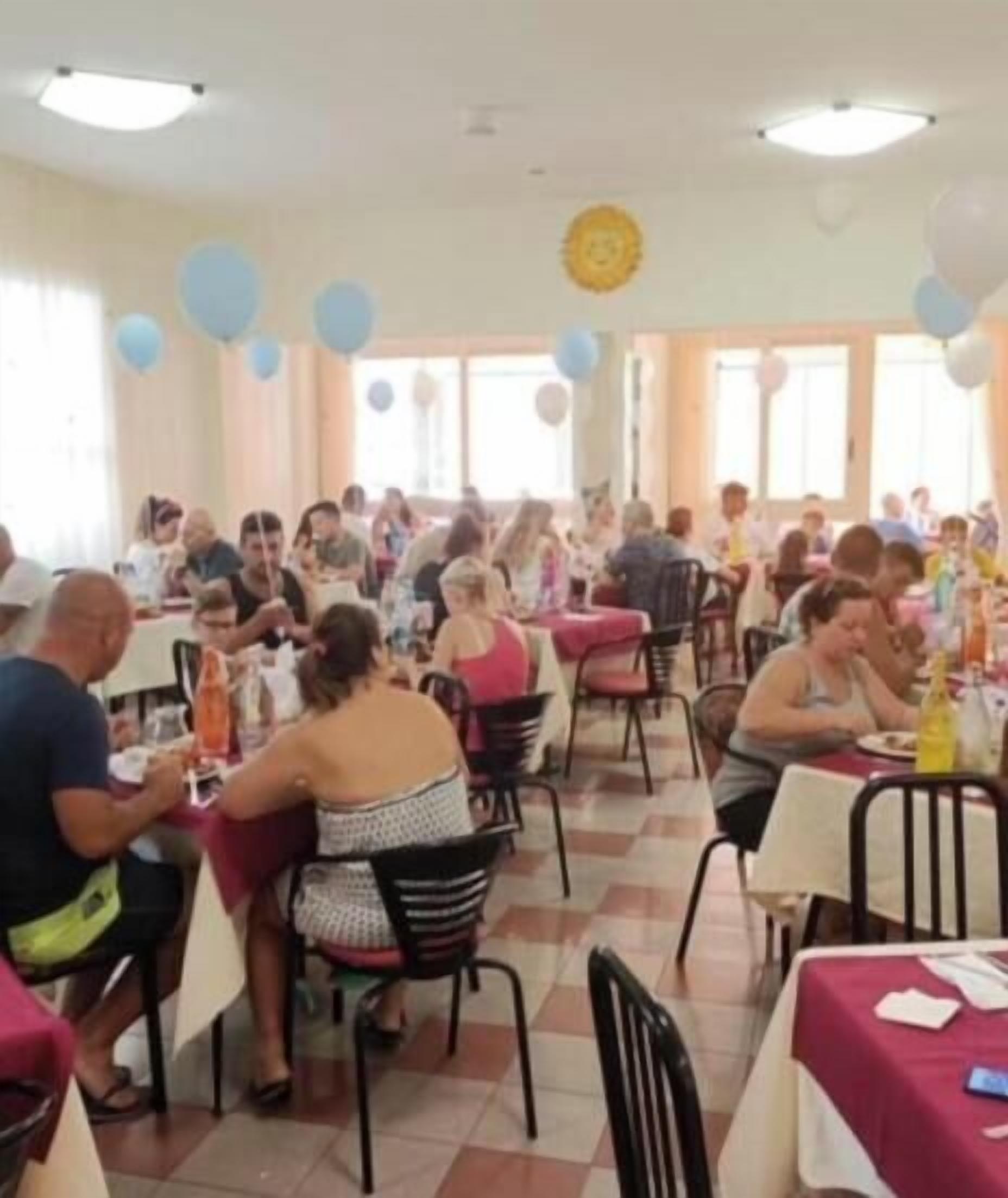 Un comedor con varias mesas y sillas, globos y un reloj en la pared.