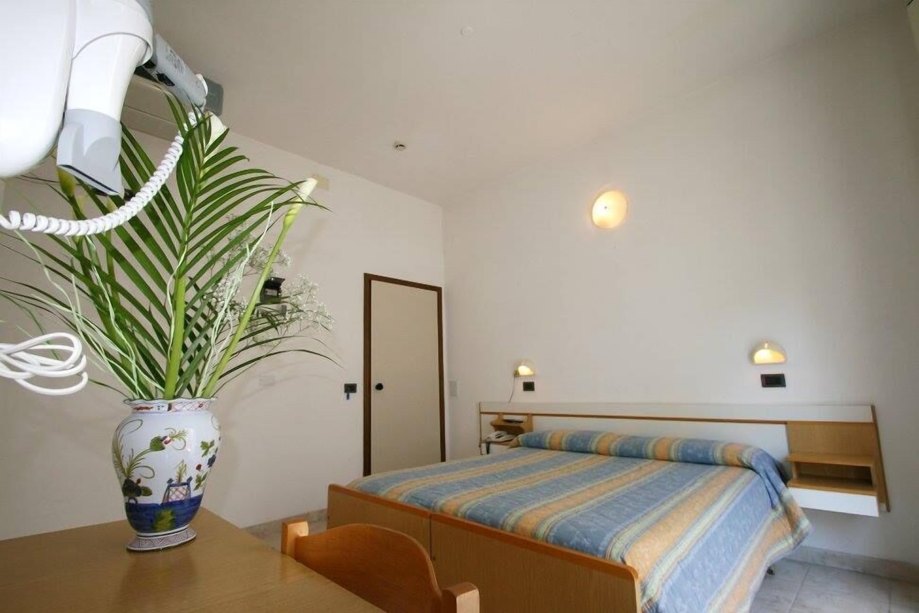 Une chambre à coucher avec un lit, une table de chevet et une plante en pot.