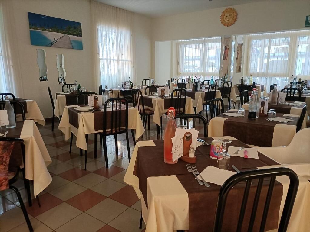 A dining area with multiple tables, chairs, and a large window.