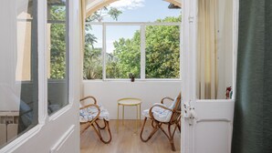 A room with two wicker chairs and a small table, a large arched window, and a view of greenery outside. - La Glacière - Ostalarià Agricol (Tresques)