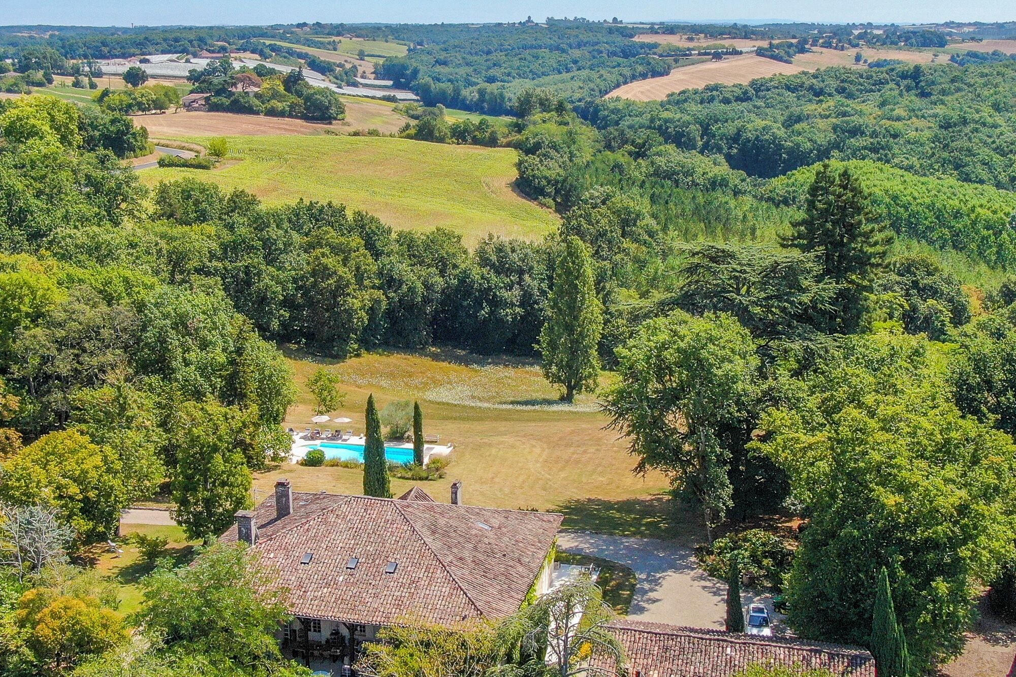 A villa with a swimming pool, surrounded by lush greenery and rolling hills.