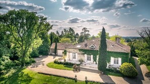 Ett stort, traditionellt hus med en välskött trädgård, en uppfart och en framträdande skorsten.