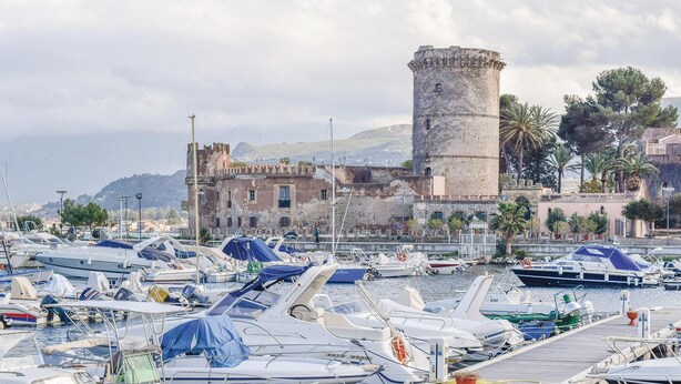 A marina with numerous boats docked, a historic building with a tower, and a mountainous backdrop. - 1 bedroom lovely apartment in San Nicola L'Arena (San Nicola L'Arena)