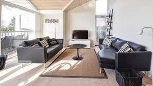 A modern living room with two black leather sofas, a small round table, and a TV on a white cabinet. There are framed pictures on the wall, a floor lamp, and a balcony with a railing. - Gorgeous home in Faaborg with WiFi (Faaborg)