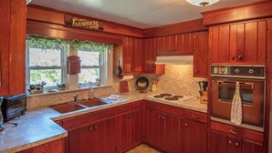 Una cocina con armarios de madera, una estufa y un lavamanos.