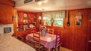 Una cocina de granja acogedora con armarios de madera, una mesa de comedor cubierta con mantel a cuadros rojo y blanco, y un letrero que dice "FARMHOUSE KITCHEN".