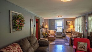 Una sala acogedora con un sofá marrón, un sillón rojo y una alfombra estampada.