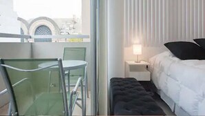 A hotel room with a balcony, a bed, a nightstand, and a chair. - HOMETANGO ABASTO (CABA)