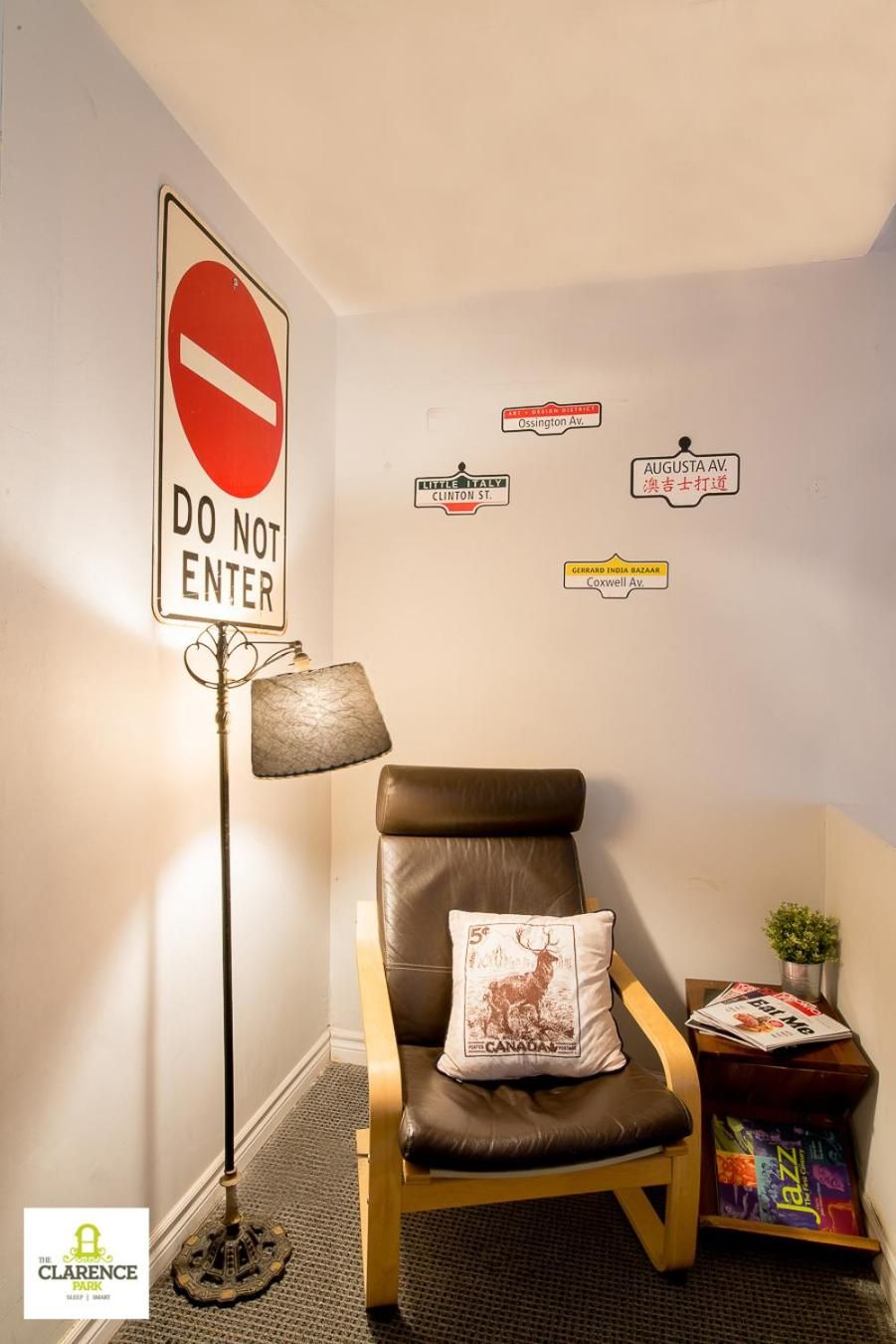 A corner room with a 'DO NOT ENTER' sign, a leather chair with a pillow, a lamp, and wall decorations including street names.