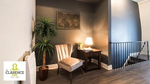 Une pièce avec une chaise, une table avec une lampe, une plante en pot et une carte accrochée au mur.