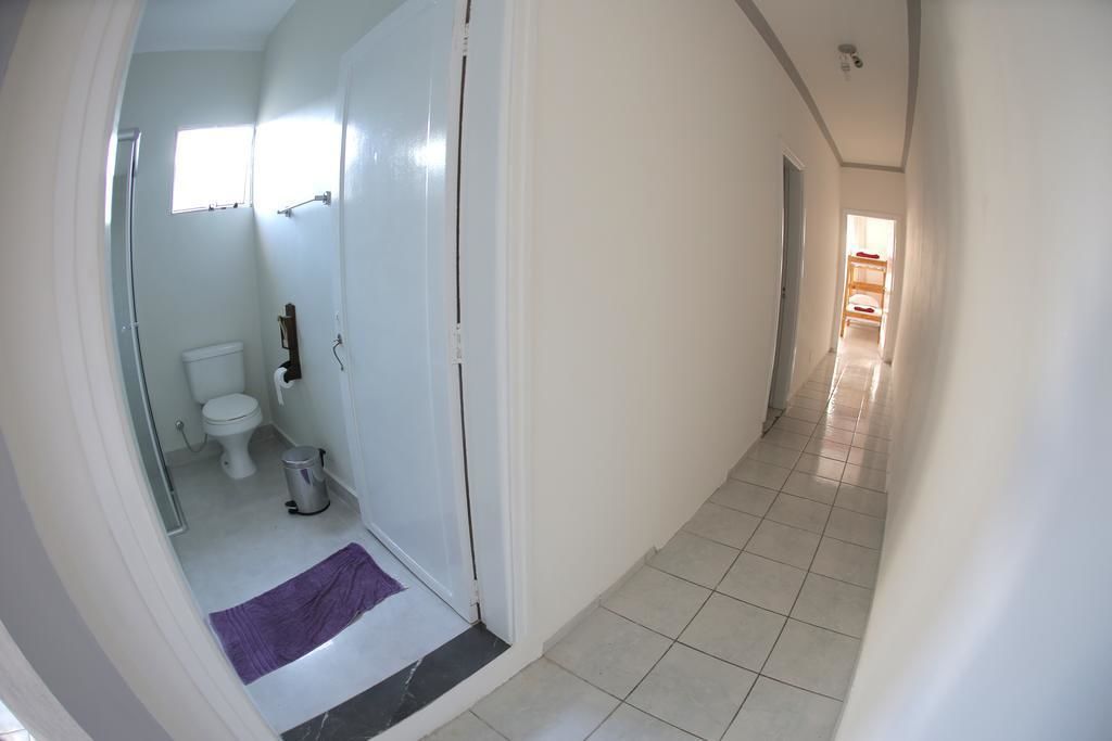 A narrow hallway with a bathroom on the left, featuring a toilet, sink, and shower.