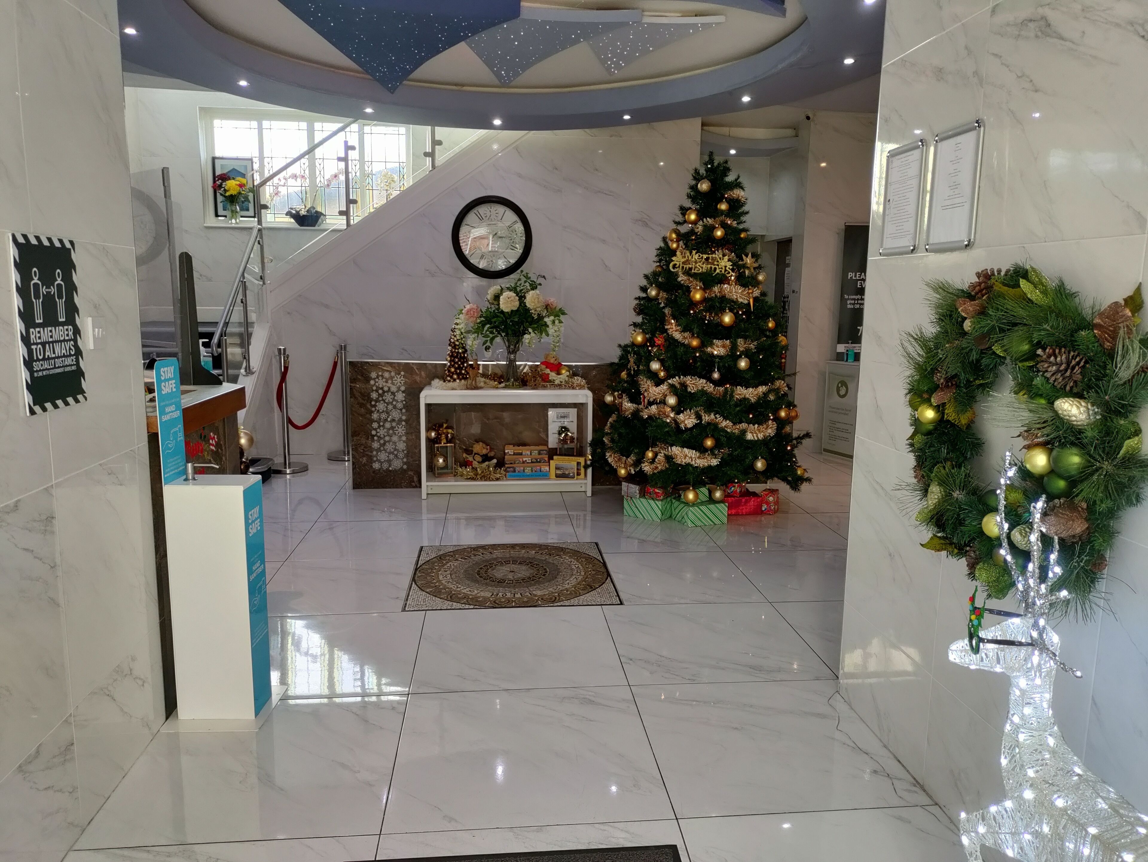 A hotel lobby with a Christmas tree, a reception desk, and a staircase.