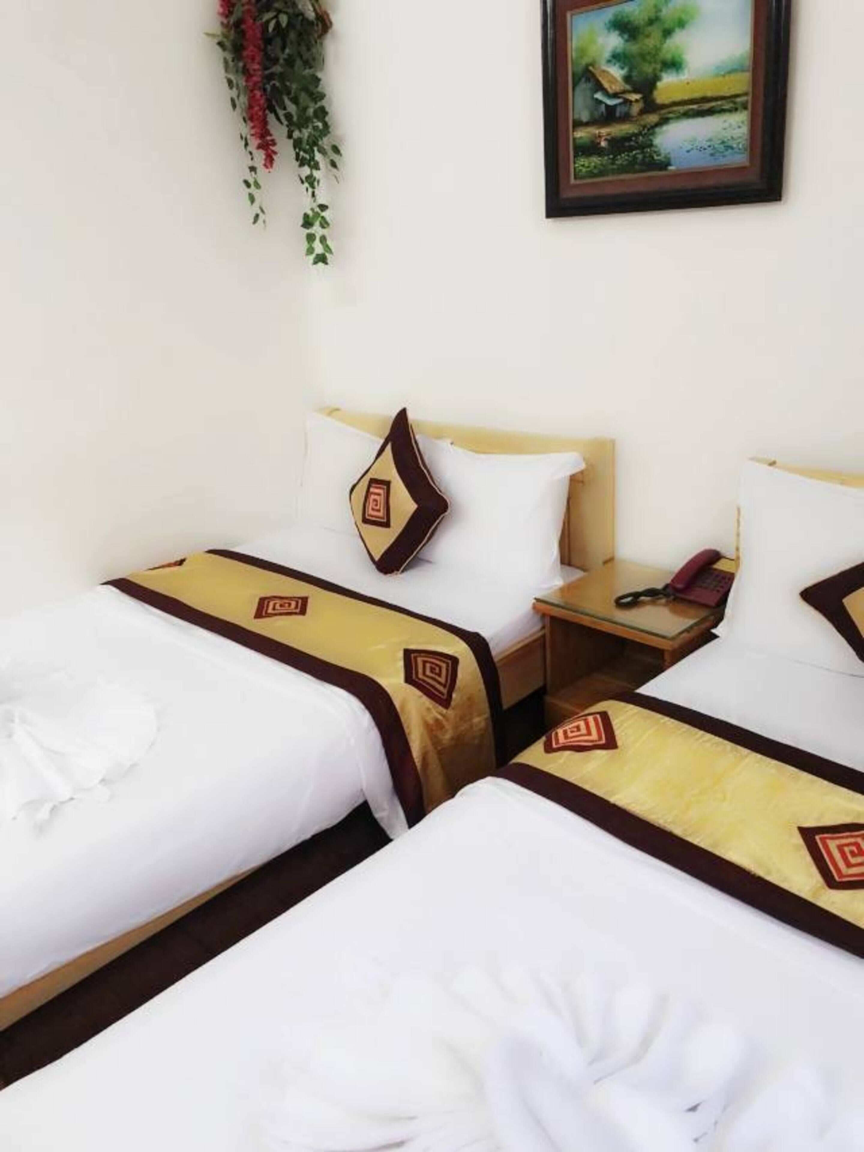A hotel room with two beds, each with a white and brown bedspread, a wooden headboard, and a small bedside table with a telephone.
