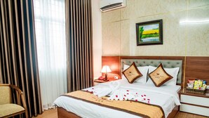 A hotel room with a bed, a chair, a nightstand, a lamp, and a painting on the wall. - OYO 1143 Thu Giang Hotel (Hanoi)