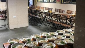 A dining area with multiple tables and chairs, some tables have bowls of food. - OYO 1143 Thu Giang Hotel (Hanoi)