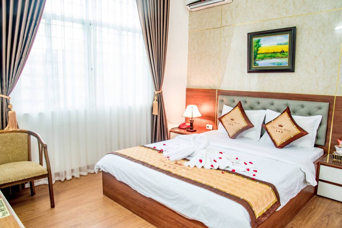 A hotel room with a bed, a nightstand, a lamp, a chair, and a painting on the wall.
