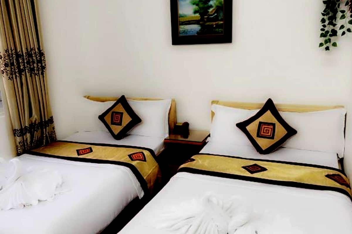A hotel room with two beds, each with white bedding and decorative pillows featuring a geometric pattern.