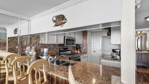 Eine moderne Küche mit Granit Arbeitsplatten, Edelstahlgeräten und Holzstühlen.