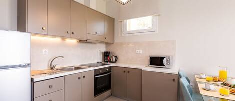 A compact kitchen with a microwave, stove, sink, and a dining area with a table and chairs.