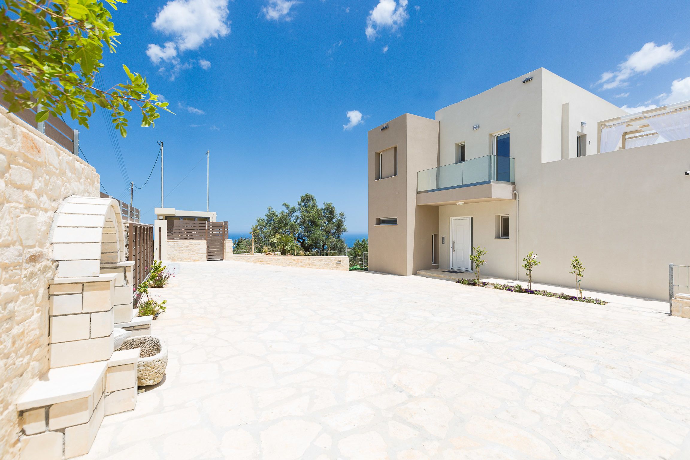 A modern building with a stone facade, a flat roof, and a clear blue sky.