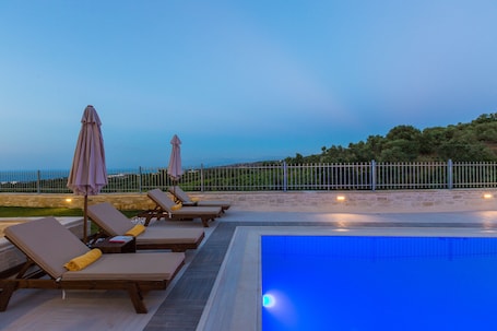 Una piscina al aire libre, sombrillas, sillones reclinables de piscina