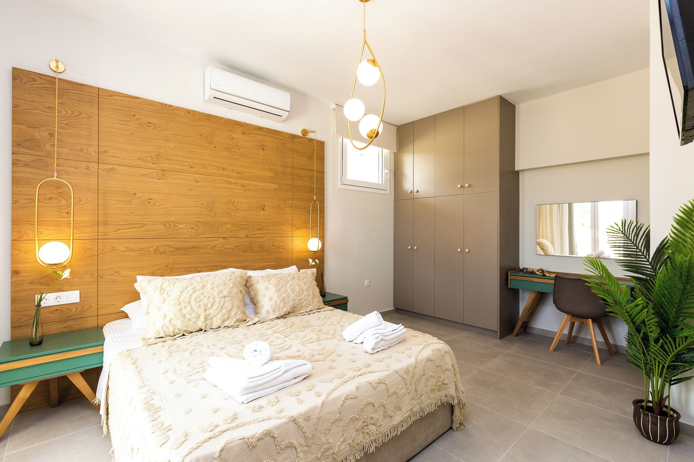 Un dormitorio moderno con cabecera de madera, un escritorio, una silla y una planta en maceta.
