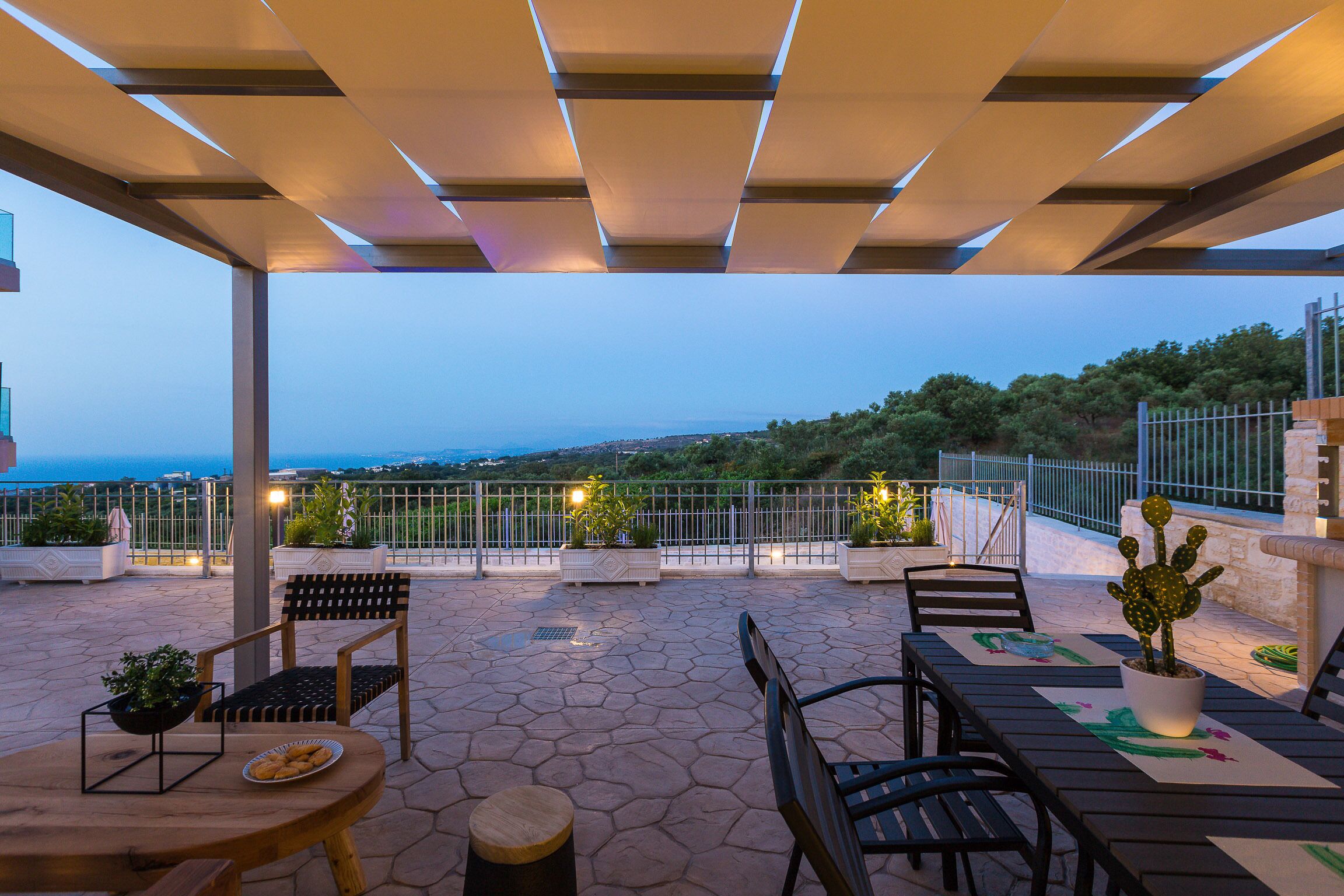 An outdoor patio with a table, chairs, and a cactus plant.