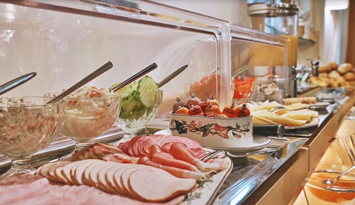 Ein Buffet mit verschiedenen Speisen, darunter Aufschnitt, Salate und Desserts.