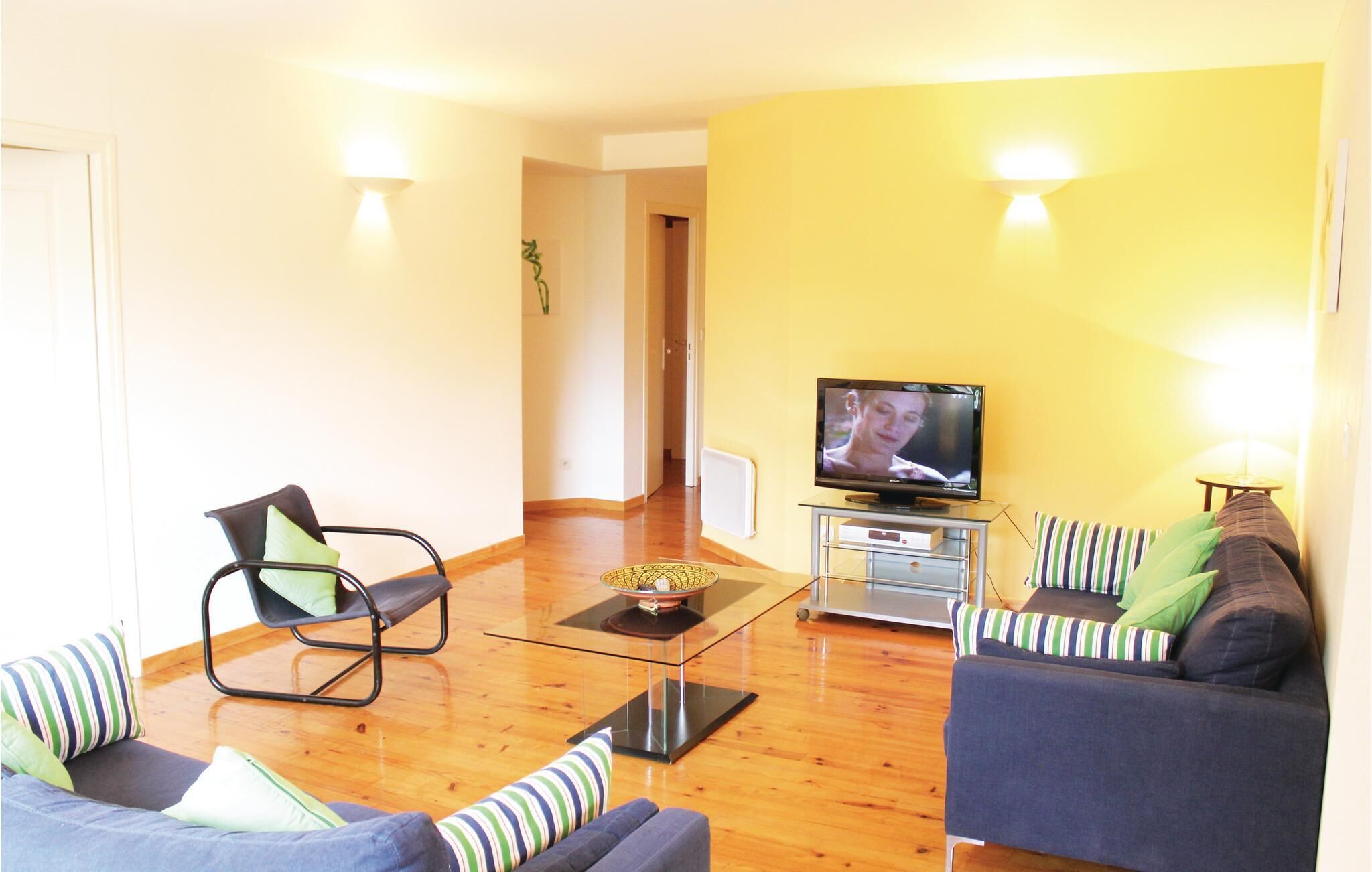 A living room with a sofa, a chair, a coffee table, and a TV.